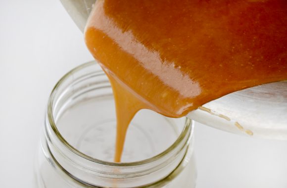 Pouring Easy Homemade Butterscotch Sauce into mason jar