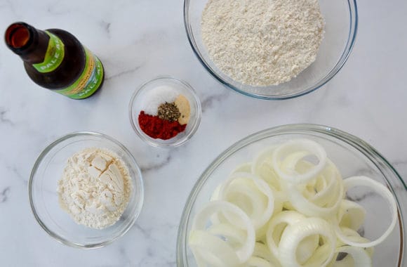 Glass bowls containing spices, flour and sliced onions