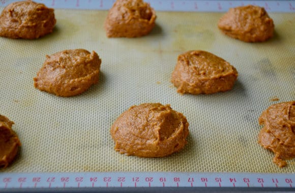 A baking sheet with mounds of pumpkin whoopie pie batter