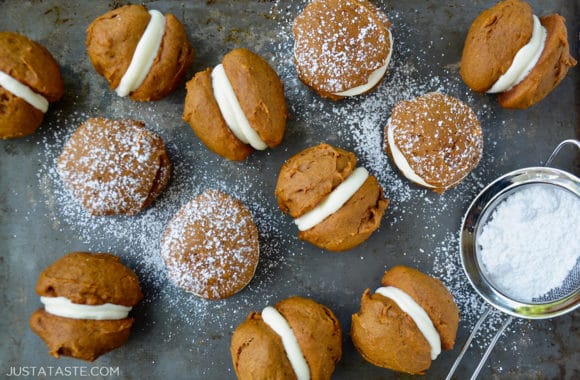 A baking sheet with pumpkin whoopie pies dusted with confectioners' sugar