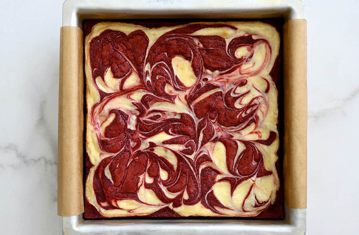 A top-down view of baked red velvet brownies in a parchment paper-lined pan