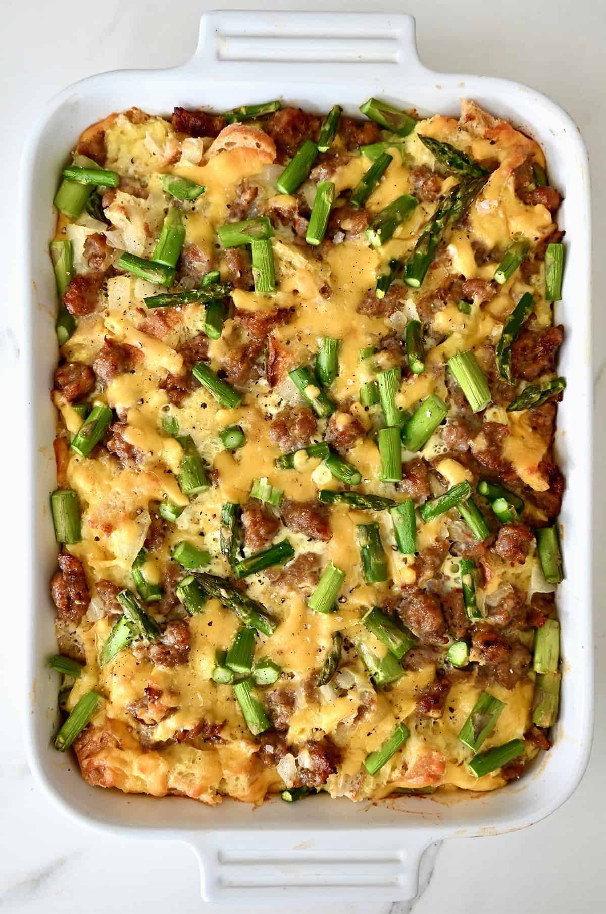 Baked breakfast casserole with sausage and asparagus in a 9x13 pan.