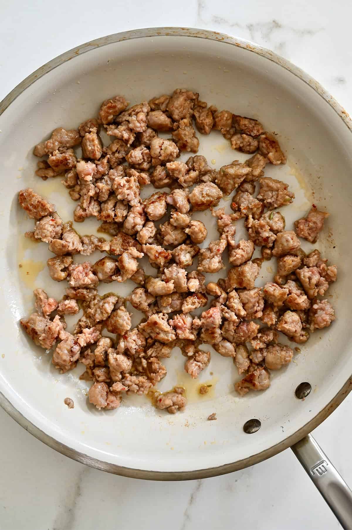 Cooked and crumbled sausage in a skillet.
