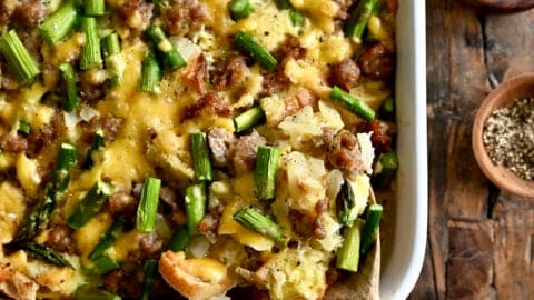 Overnight breakfast strata with sausage and asparagus in a 9x13 baking dish.