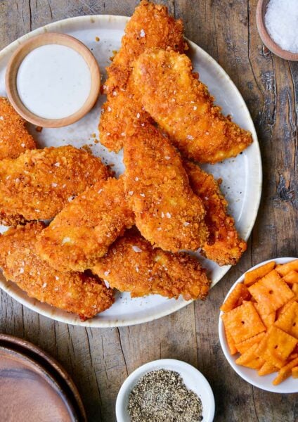 Crispy Baked Cheddar-Dijon Chicken Tenders on a white plate next to a small ramekin with ranch