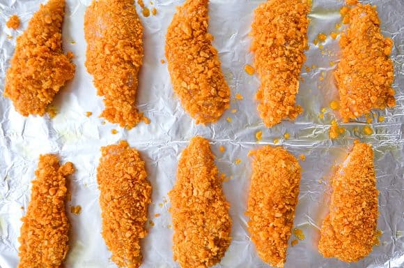 Cheddar chicken tenders on baking sheet lined with foil