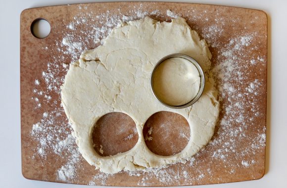 Shortcake biscuit dough on floured cutting board with circular shapes cut out. 