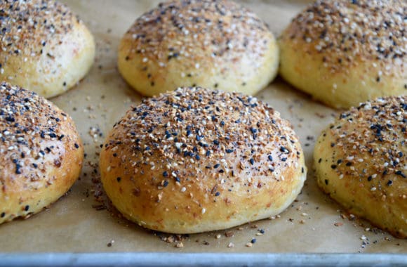 A baking sheet with burger buns topped with everything seasoning