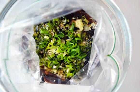 The Ultimate Asian Flank Steak Marinade topped with scallions in plastic bag