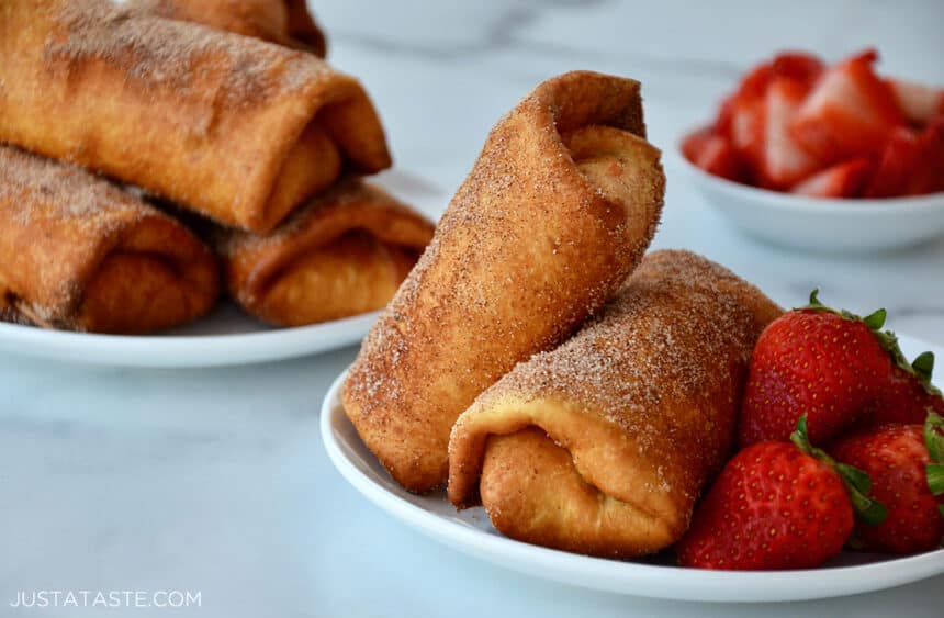 Strawberry Cheesecake Chimichangas on a white plate next to fresh strawberries