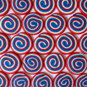A top-down view of rows of red, white and blue pinwheel icebox cookies.
