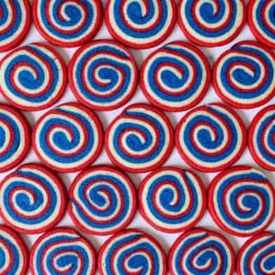 A top-down view of rows of red, white and blue pinwheel icebox cookies.