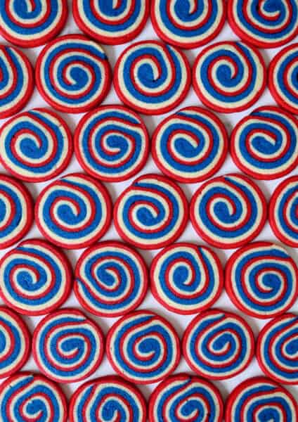 A top-down view of rows of red, white and blue pinwheel icebox cookies.