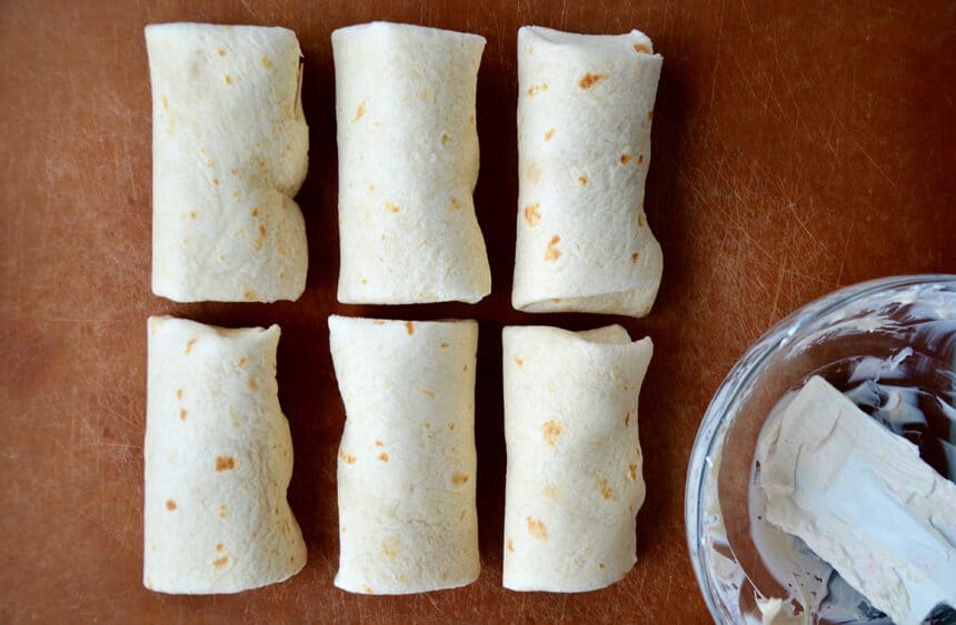 Rolled tortillas on wooden cutting board
