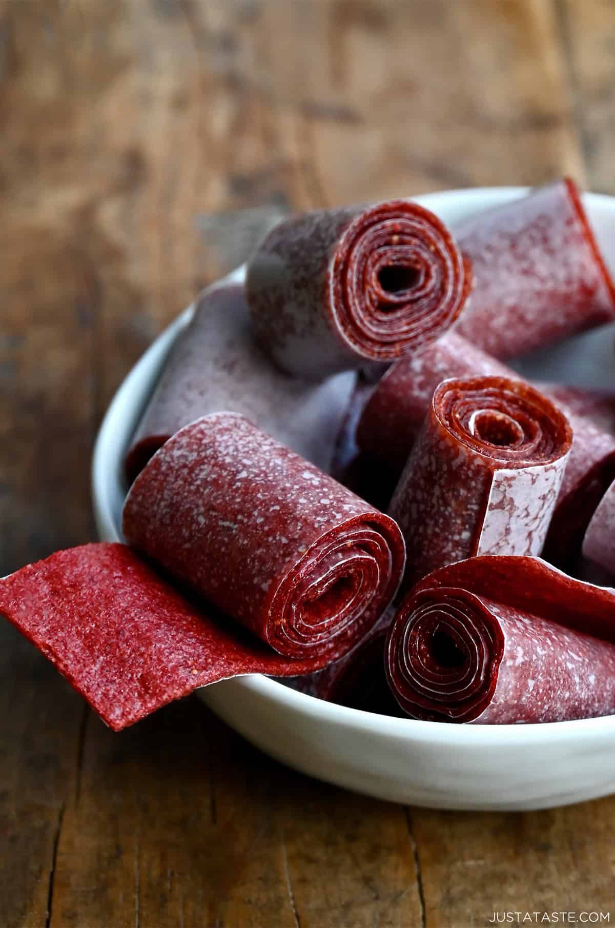 Homemade strawberry fruit roll-ups in a white bowl.