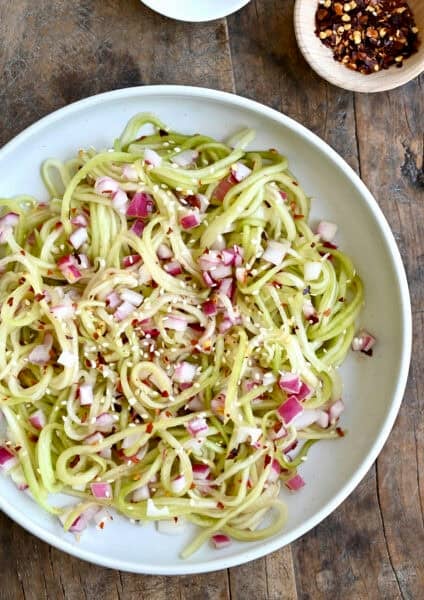 Asian cucumber noodles with diced red onion, red pepper flakes, and sesame seeds all tossed in a simple sweet and sour dressing.