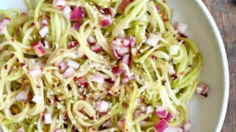 Asian cucumber noodles with diced red onion, red pepper flakes, and sesame seeds all tossed in a simple sweet and sour dressing.