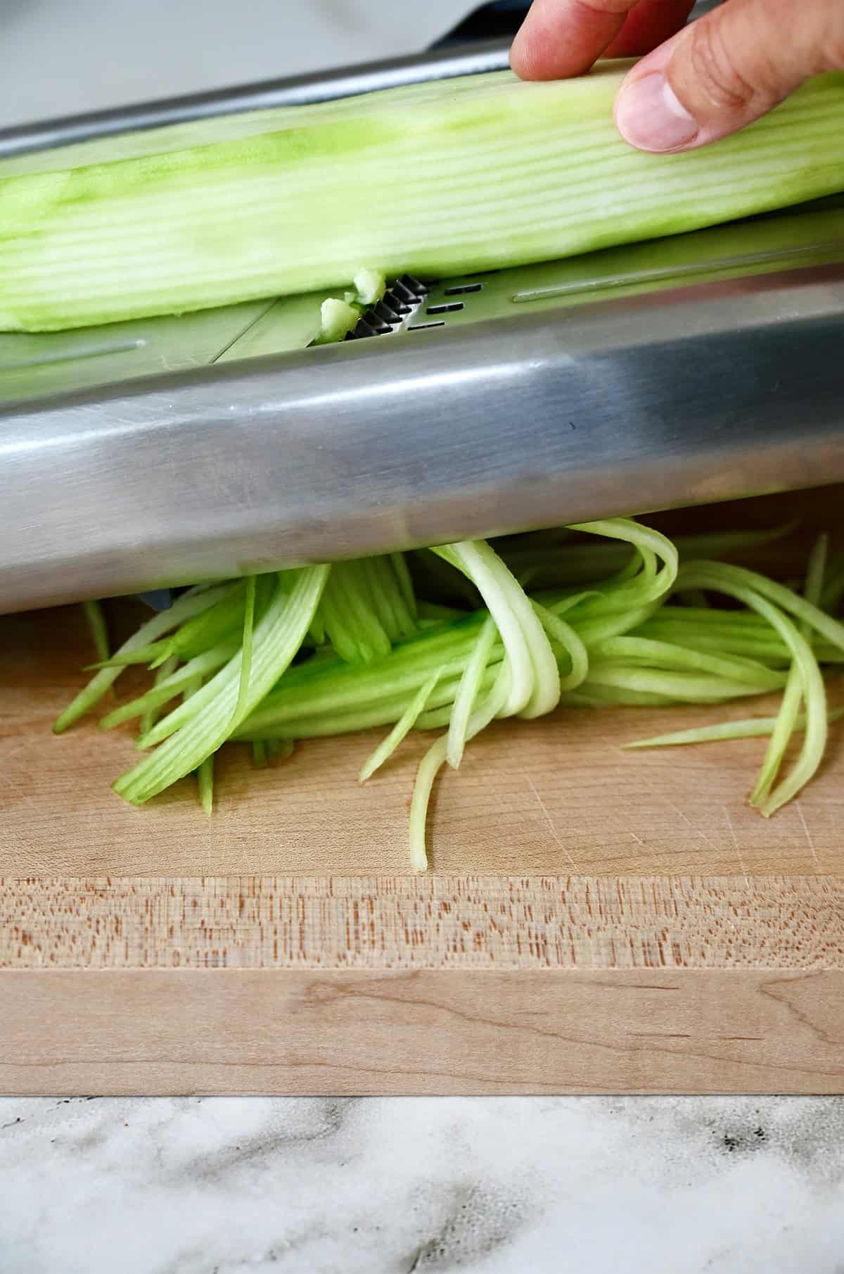 Making cucumber noodles by using a mandoline.