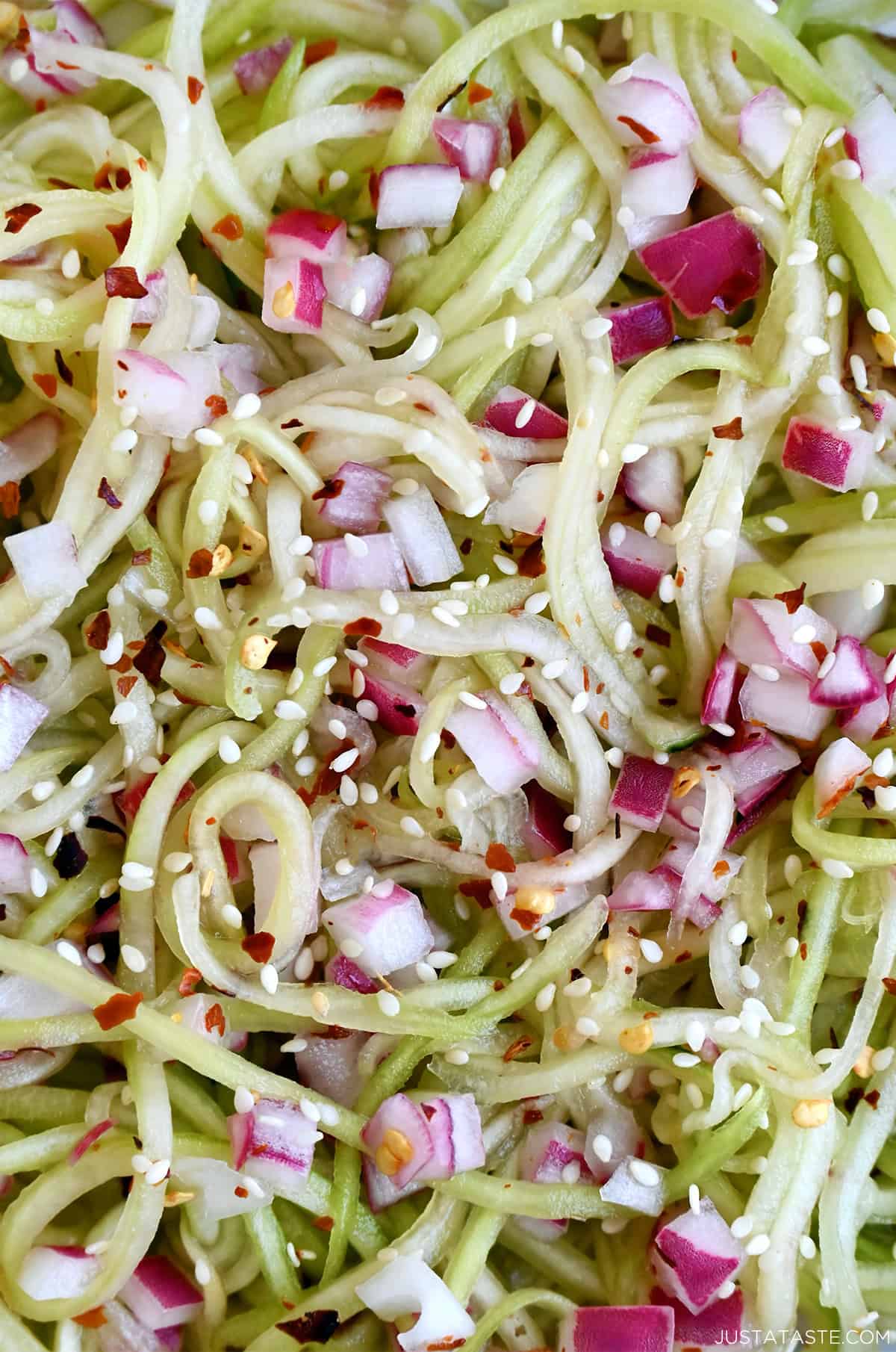 Sweet and sour cucumber salad with diced red onions and sesame seeds.