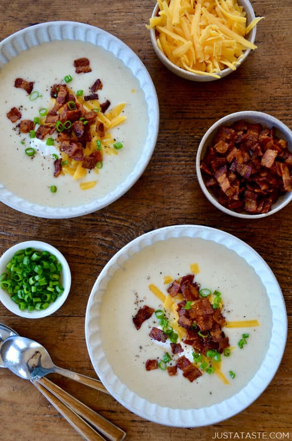 Top-down view of two white bowls containing Loaded Baked Potato Soup garnished with bacon, cheddar cheese and chopped scallions