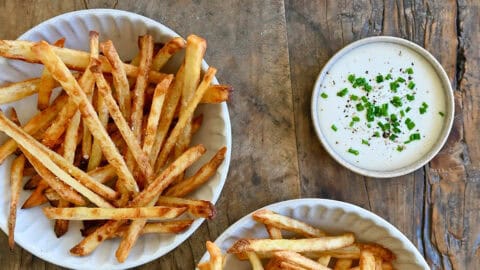 French fries three ways: deep fried, air fried and baked. Three smalls bowls containing ketchup, ranch dressing and sea salt are nearby.