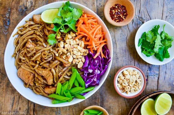 The best easy pad Thai with chicken on serving plate with cilantro, shredded carrots and purple cabbage, sliced scallions and peanuts
