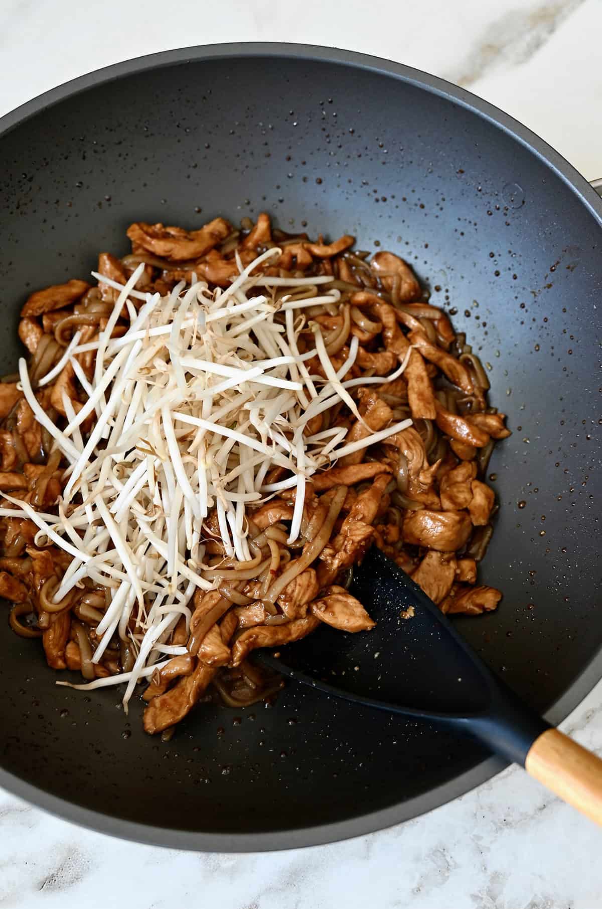 Stir-fried chicken and bean sprouts in a wok.