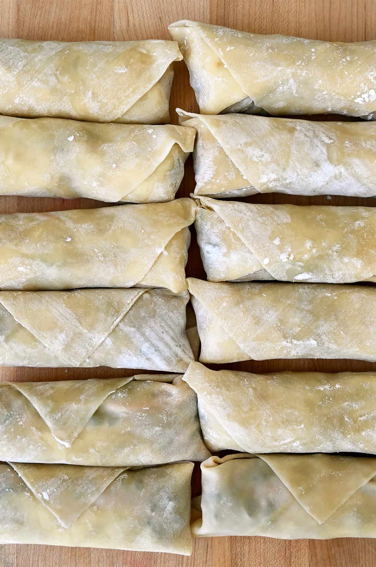 Two rows of perfectly rolled un-fried egg rolls.