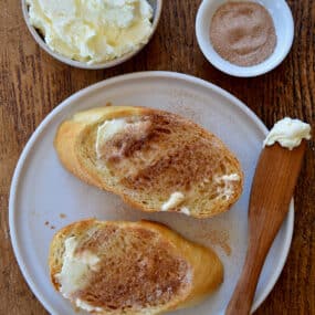 A top-down view of slices of cinnamon-sugar toast with a small bowl of butter