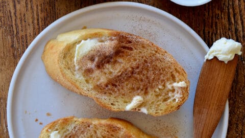 A top-down view of slices of cinnamon-sugar toast with a small bowl of butter