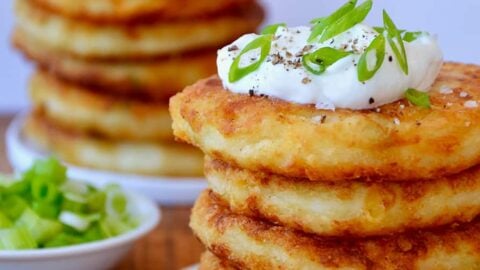 Stacks of mashed potato pancakes topped with sour cream and scallions