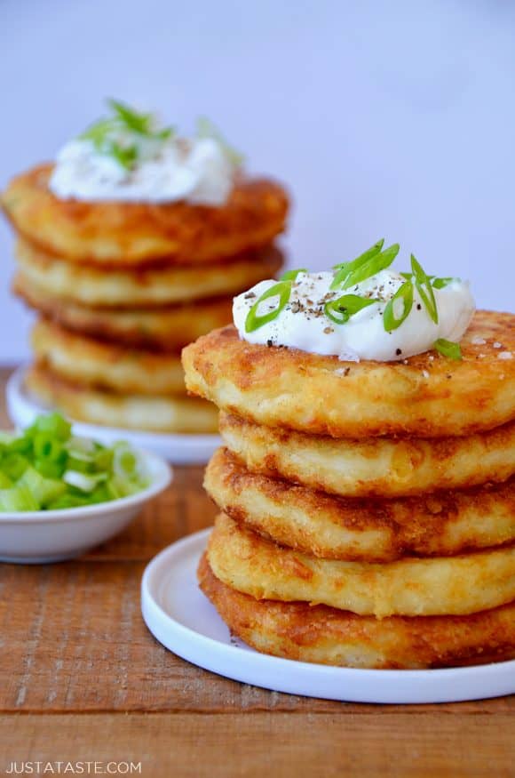 Stacks of mashed potato pancakes topped with sour cream and scallions