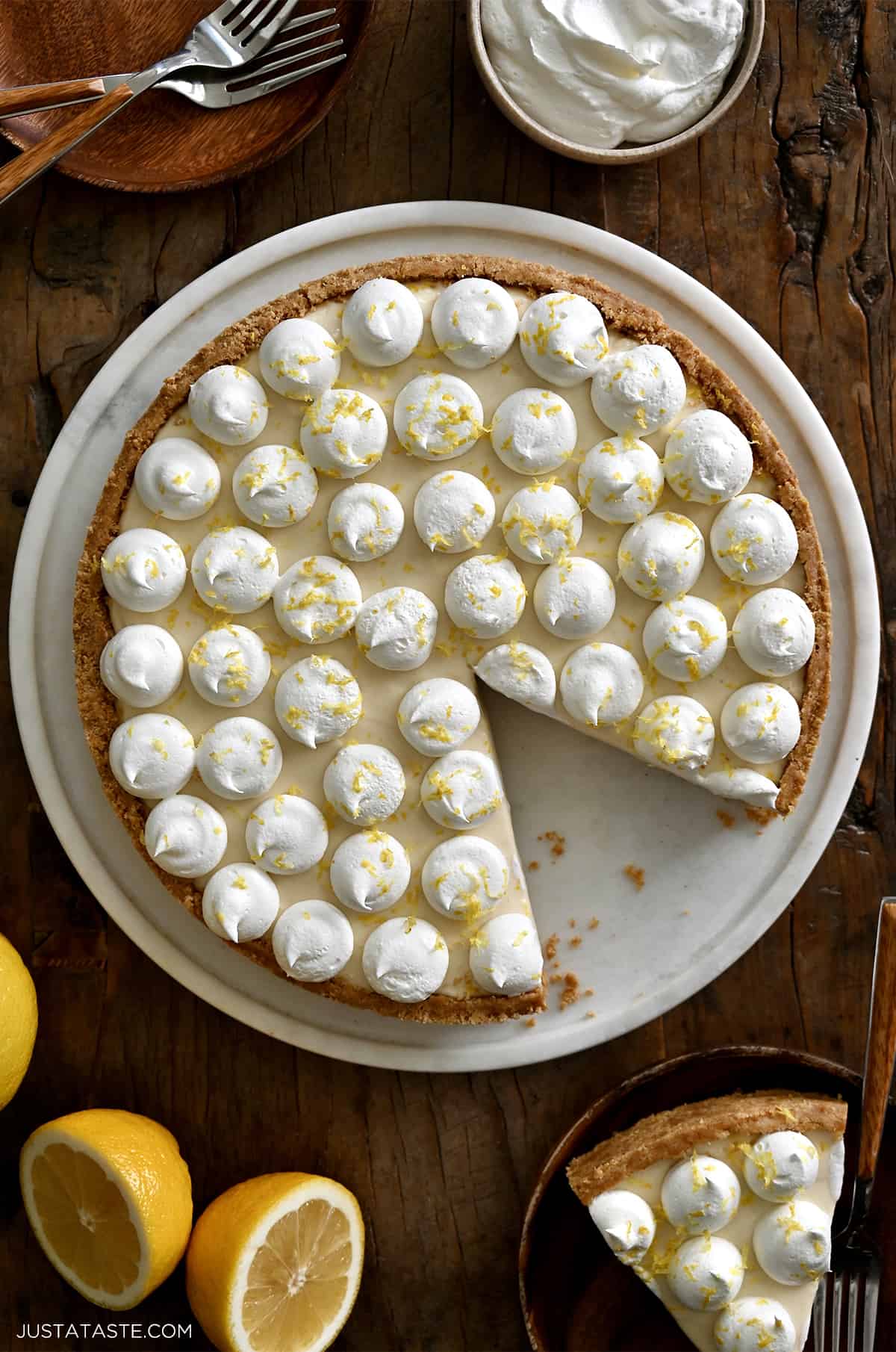 A top-down view of a cheesecake topped with dollops of whipped cream and lemon zest.