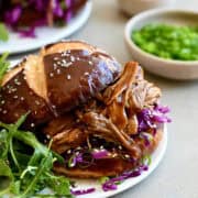 Balsamic honey pulled pork sandwich on a plate with arugula.