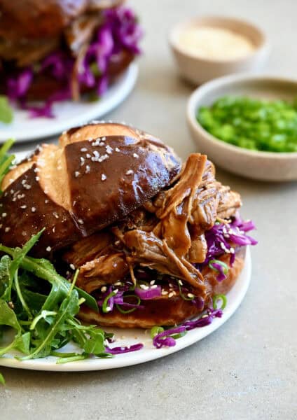Balsamic honey pulled pork sandwich on a plate with arugula.