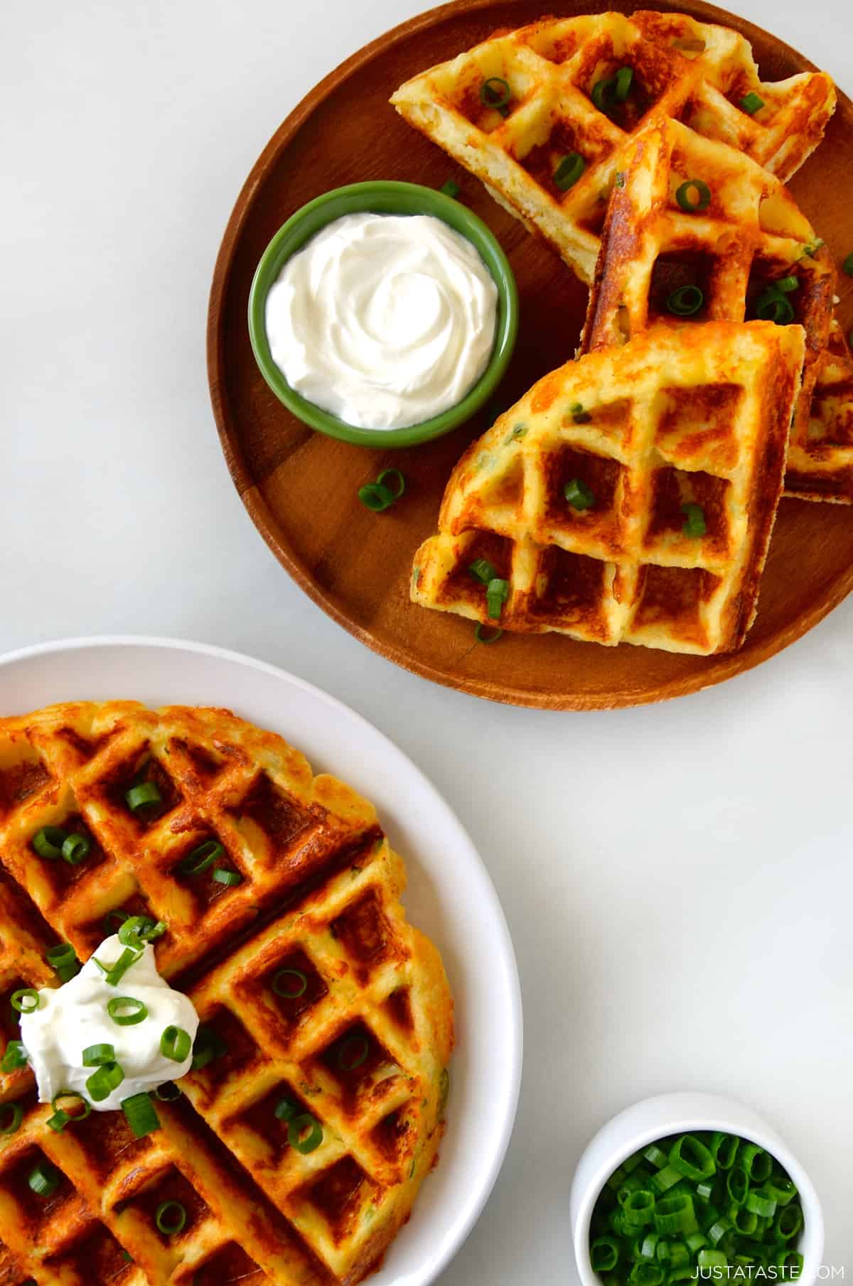 Two plates containing mashed potato waffles topped with sour cream.