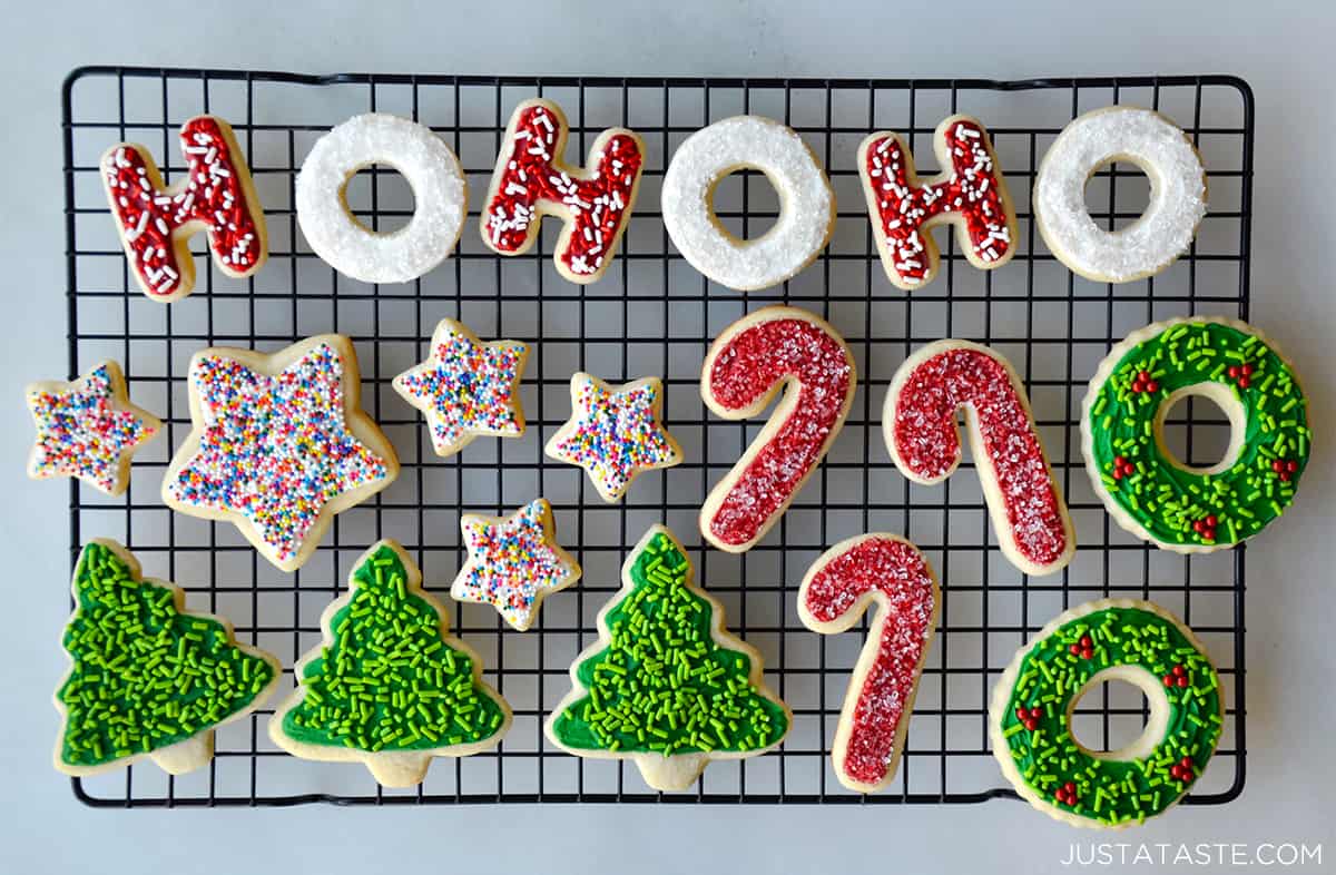 Christmas-themed sugar cookies with red, green ,and white frosting and sprinkles on a wire cooling rack.