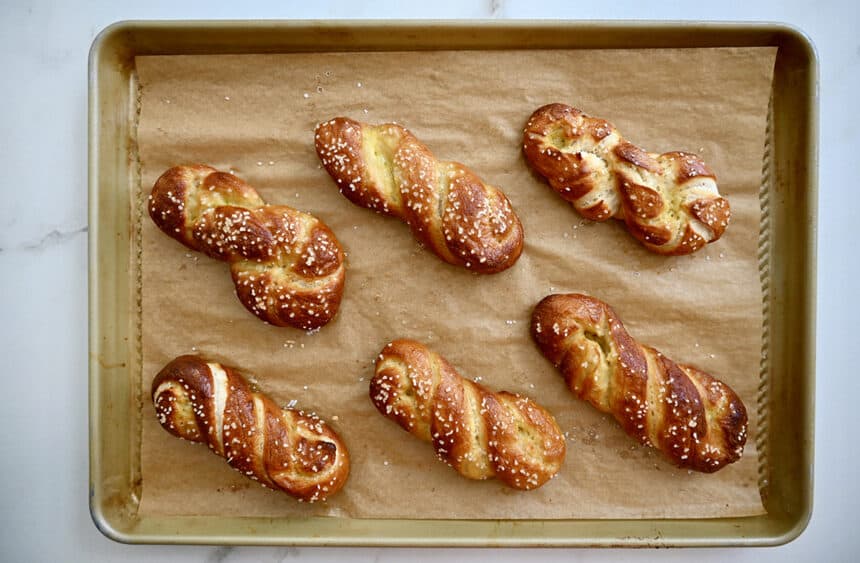 A top-down view of golden brown soft pretzels on a parchment paper-lined baking sheet