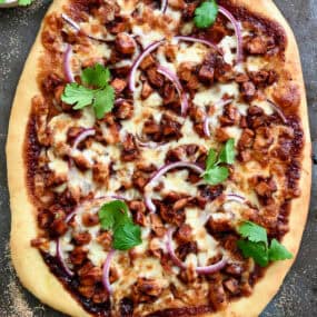 BBQ chicken pizza with barbecue sauce, red onion, shredded chicken, mozzarella cheese and fresh cilantro.