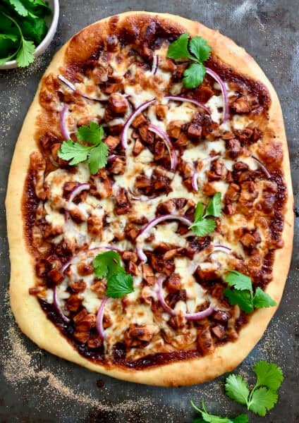 BBQ chicken pizza with barbecue sauce, red onion, shredded chicken, mozzarella cheese and fresh cilantro.
