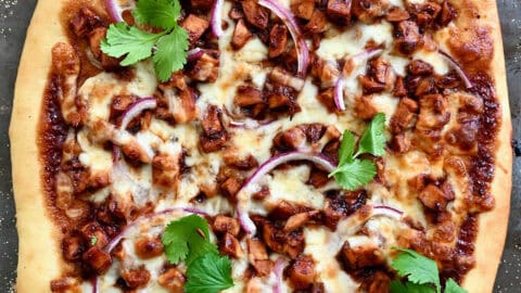 BBQ chicken pizza with barbecue sauce, red onion, shredded chicken, mozzarella cheese and fresh cilantro.