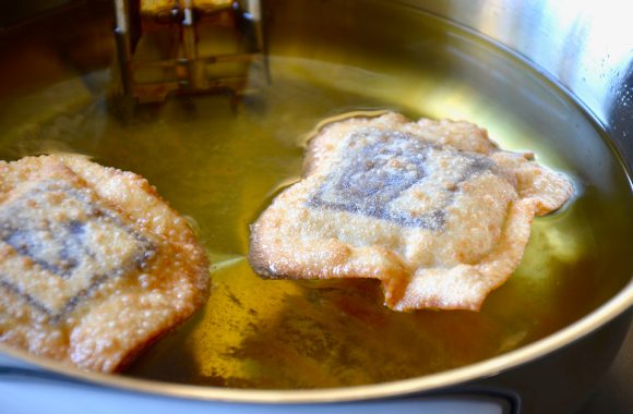 A pot of oil with chocolate wontons being deep-fried inside