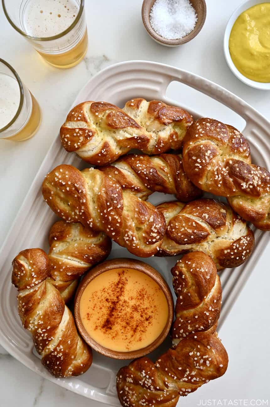 A top-down view of a serving platter containing soft pretzel twists and a small bowl containing beer cheese dip