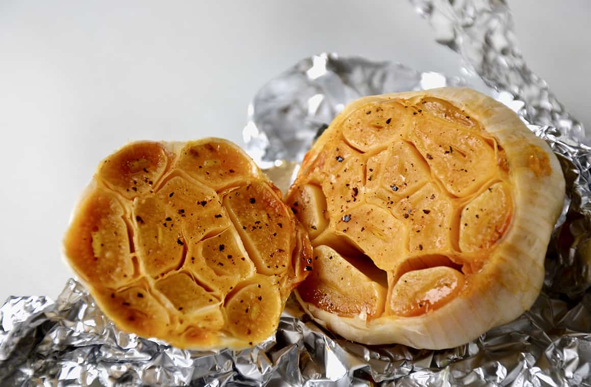 A head of roasted garlic atop aluminum foil