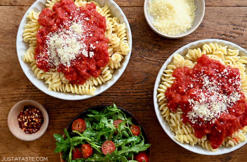 A top-down view of two bowls containing pasta topped with easy homemade marinara sauce garnished with Parmesan cheese