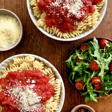 A top-down view of two bowls containing 10-Minute Homemade Marinara Sauce atop rotini pasta