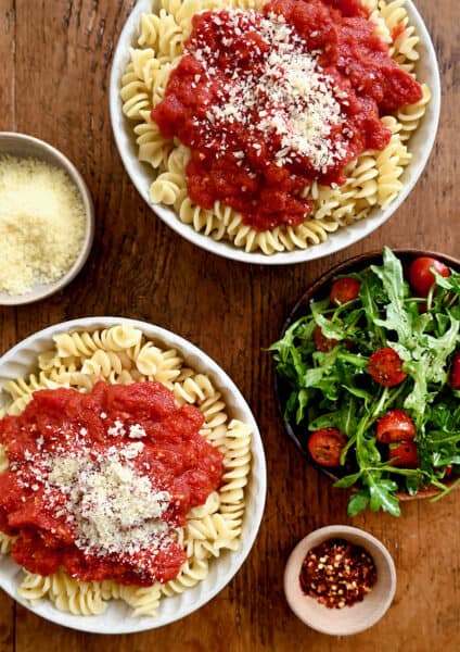 A top-down view of two bowls containing 10-Minute Homemade Marinara Sauce atop rotini pasta