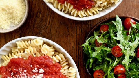 A top-down view of two bowls containing 10-Minute Homemade Marinara Sauce atop rotini pasta