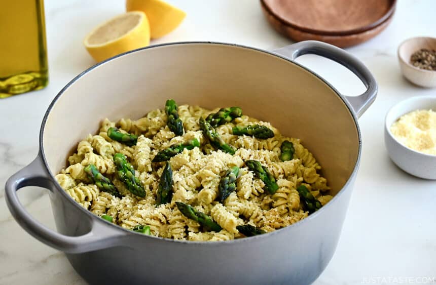 Creamy asapagus pesto pasta garnished with asparagus spears and Parmesan cheese in a large stockpot