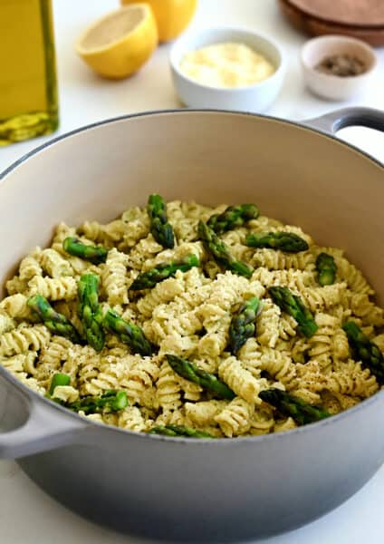 A large stockpot containing Cheesy Asparagus Pesto Pasta with fresh asparagus pieces